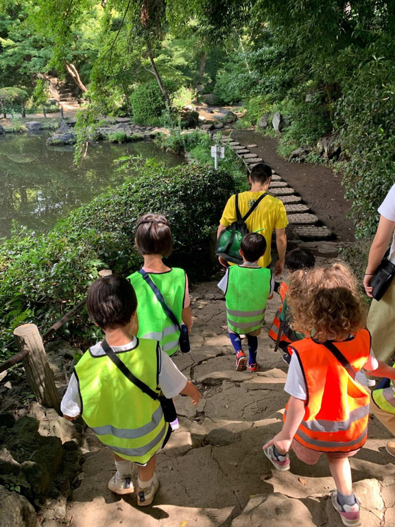 Children move toward the pond on uneven stone steps, watching one another.